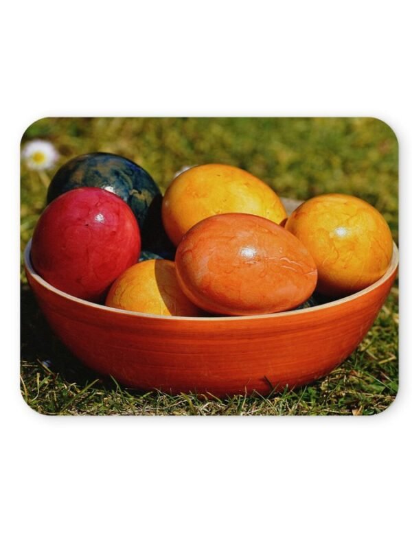 Színes húsvéti tojások egy fa tálban, zöld fűben.