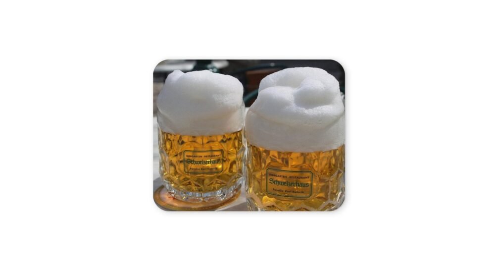 Két pohár sör sűrű habbal, egy egérpadon.