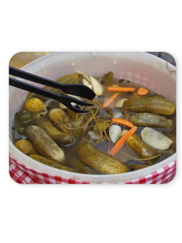 Uborkák ecetes lében, csipesz látható a képben.